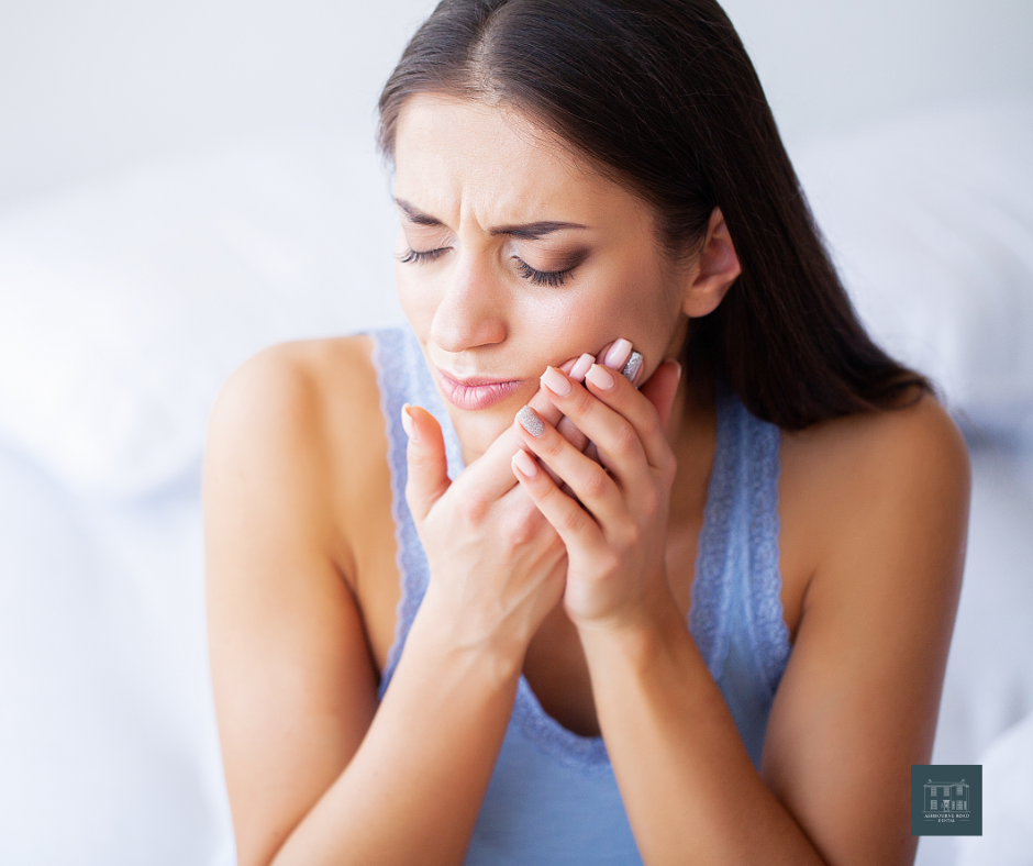 Middle-aged woman clutching her cheek in pain. 